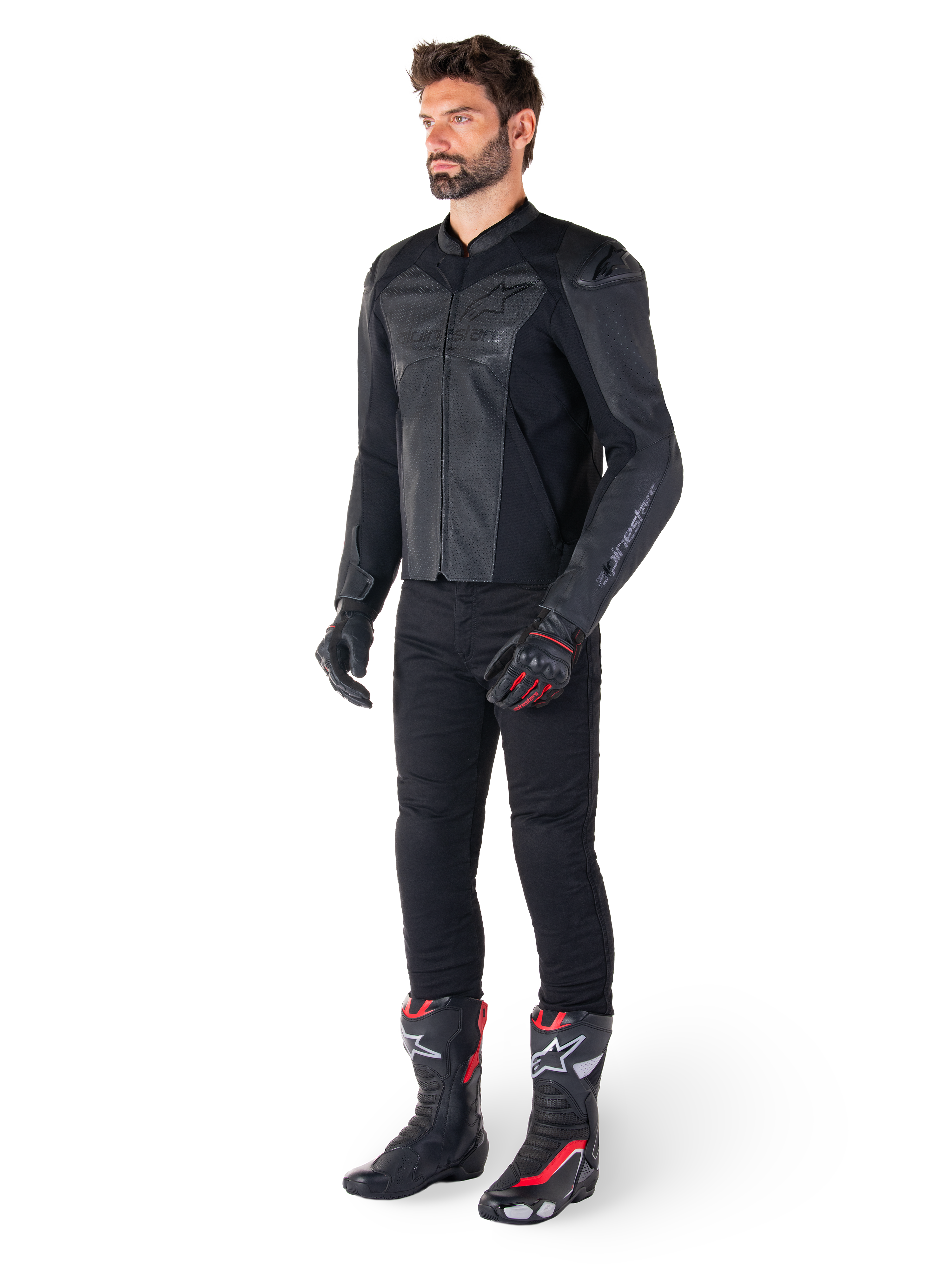 Uomo che indossa la giacca in pelle Alpinestars Faster V3 Airflow in Nero Nero, abbinata a pantaloni neri, guanti da moto neri e rossi e stivali da corsa neri con dettagli rossi e bianchi, equipaggiamento da guida sportiva completo