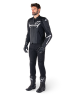 Giacca in pelle Alpinestars Faster V3 Airflow, nero e bianco, con pelle traforata e loghi Alpinestars bianchi, indossata con pantaloni da moto neri, guanti e stivali, equipaggiamento da moto sportivo