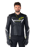 Giacca in pelle Alpinestars Faster V3 Airflow, nero, bianco e giallo fluo, indossata da un modello maschile con guanti neri coordinati, con pannelli in pelle traforata per la ventilazione ed evidente marchio Alpinestars sul petto, abbigliamento sportivo per motociclismo