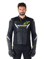 Giacca in pelle Alpinestars Faster V3 Airflow, nero, bianco e giallo fluo, indossata da un modello maschile con guanti neri coordinati, con pannelli in pelle traforata per la ventilazione ed evidente marchio Alpinestars sul petto, abbigliamento sportivo per motociclismo