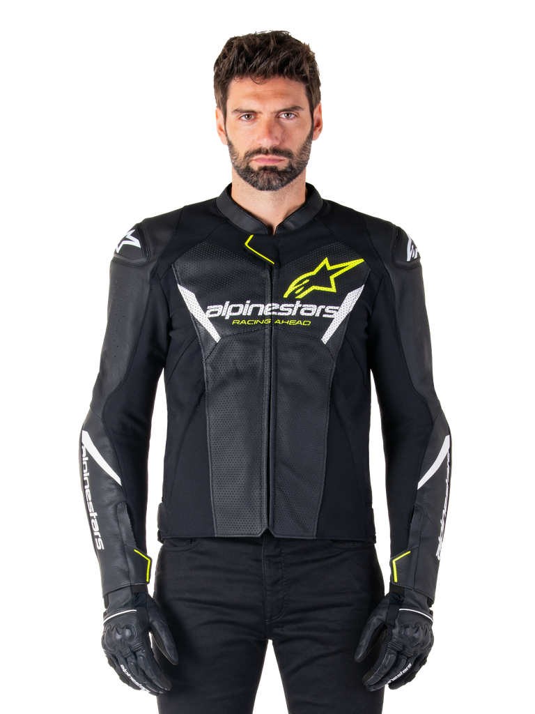 Giacca in pelle Alpinestars Faster V3 Airflow, nero, bianco e giallo fluo, indossata da un modello maschile con guanti neri coordinati, con pannelli in pelle traforata per la ventilazione ed evidente marchio Alpinestars sul petto, abbigliamento sportivo per motociclismo