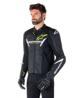 Giacca in pelle Alpinestars Faster V3 Airflow, giacca da moto sportiva, nero, bianco e giallo fluo, indossata da un uomo, con pelle traforata per la ventilazione, loghi Alpinestars su petto e braccia, abbinata a guanti neri