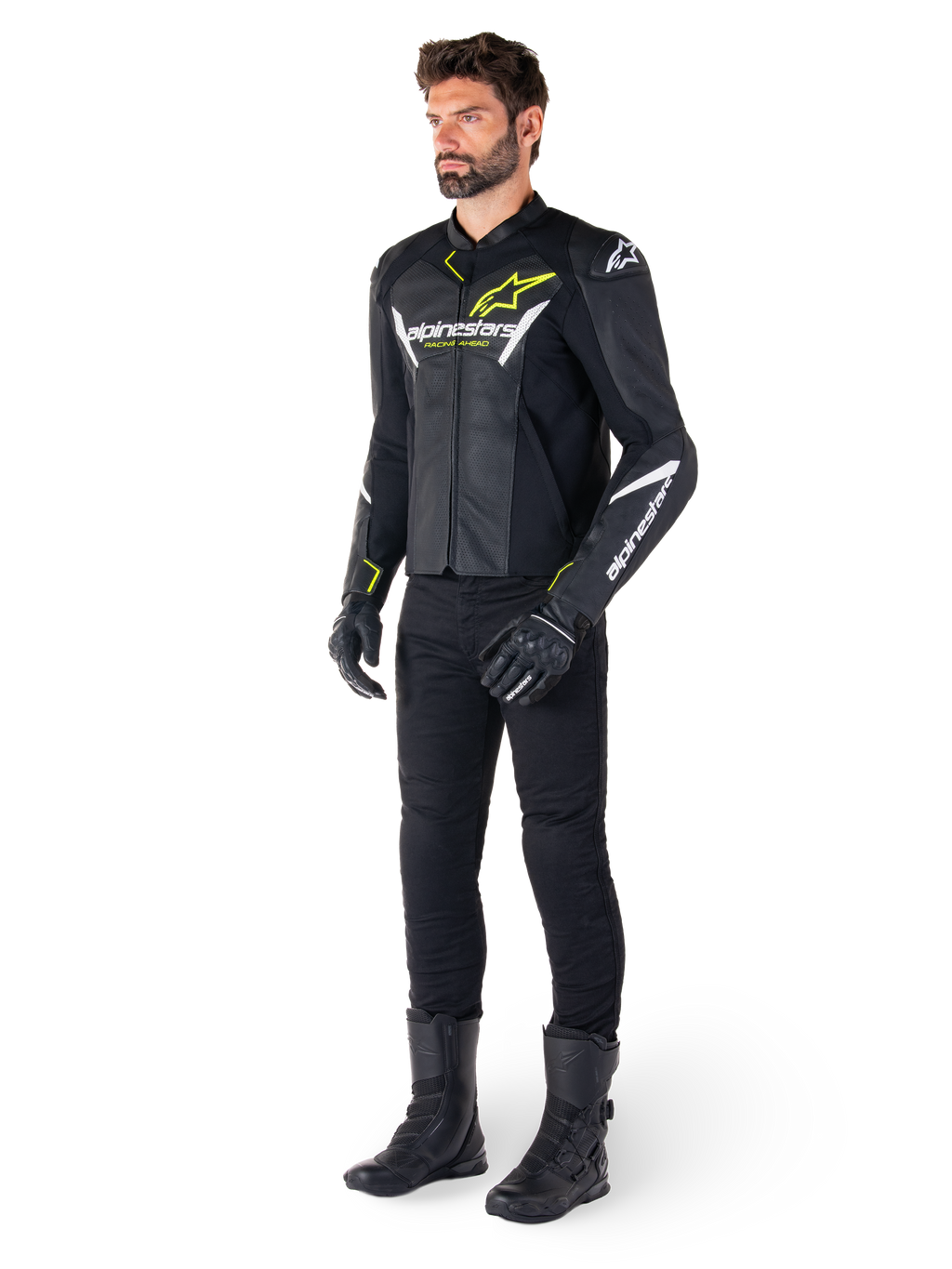 Pilota uomo che indossa la giacca in pelle Alpinestars Faster V3 Airflow in nero, bianco e giallo fluo, abbinata a pantaloni e stivali da moto neri, con pannelli in pelle traforata, dettagli del logo bianchi e accenti giallo neon, abbigliamento tecnico sportivo professionale