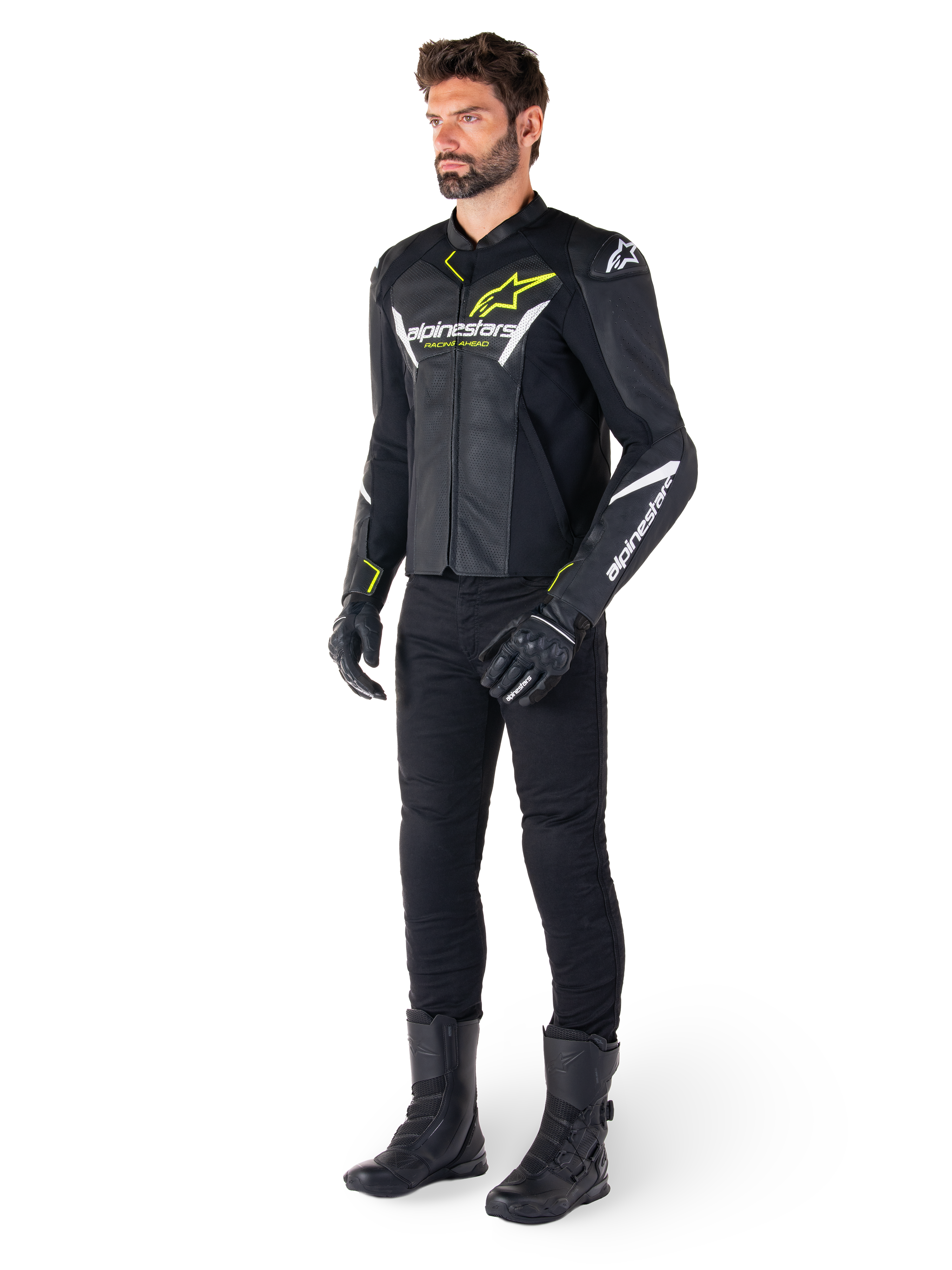 Pilota uomo che indossa la giacca in pelle Alpinestars Faster V3 Airflow in nero, bianco e giallo fluo, abbinata a pantaloni e stivali da moto neri, con pannelli in pelle traforata, dettagli del logo bianchi e accenti giallo neon, abbigliamento tecnico sportivo professionale