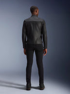 Giacca in pelle Alpinestars Blacktrack, vista posteriore, pelle bovina premium completamente nera, con pannelli a fisarmonica sulle scapole per la mobilità, indossata con pantaloni neri slim-fit e stivali neri, abbigliamento da moto urban contemporary.