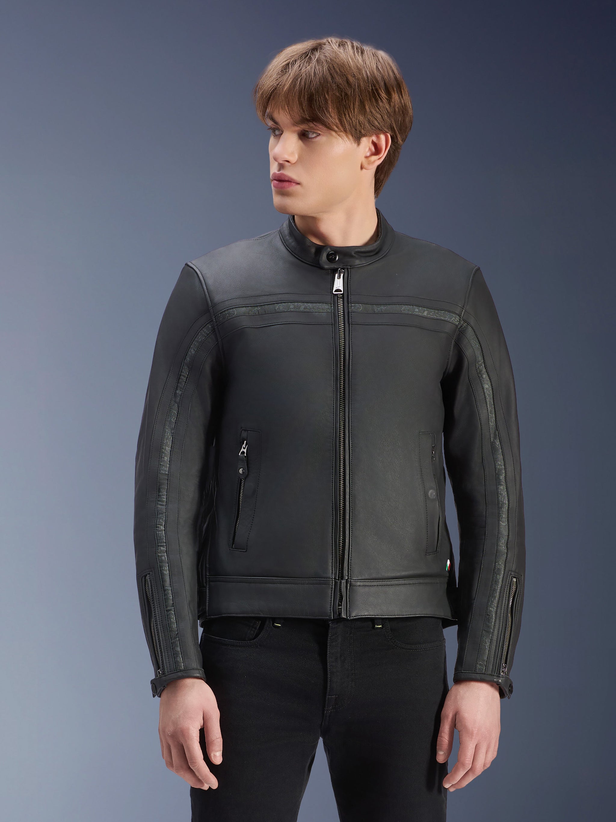 Giacca in pelle Alpinestars Dyno, nero, giacca da moto in pregiata pelle bovina, indossata da un modello con pantaloni neri, design d'ispirazione heritage con cerniera centrale e colletto alla coreana a profilo basso, abbigliamento da moto urban contemporary.
