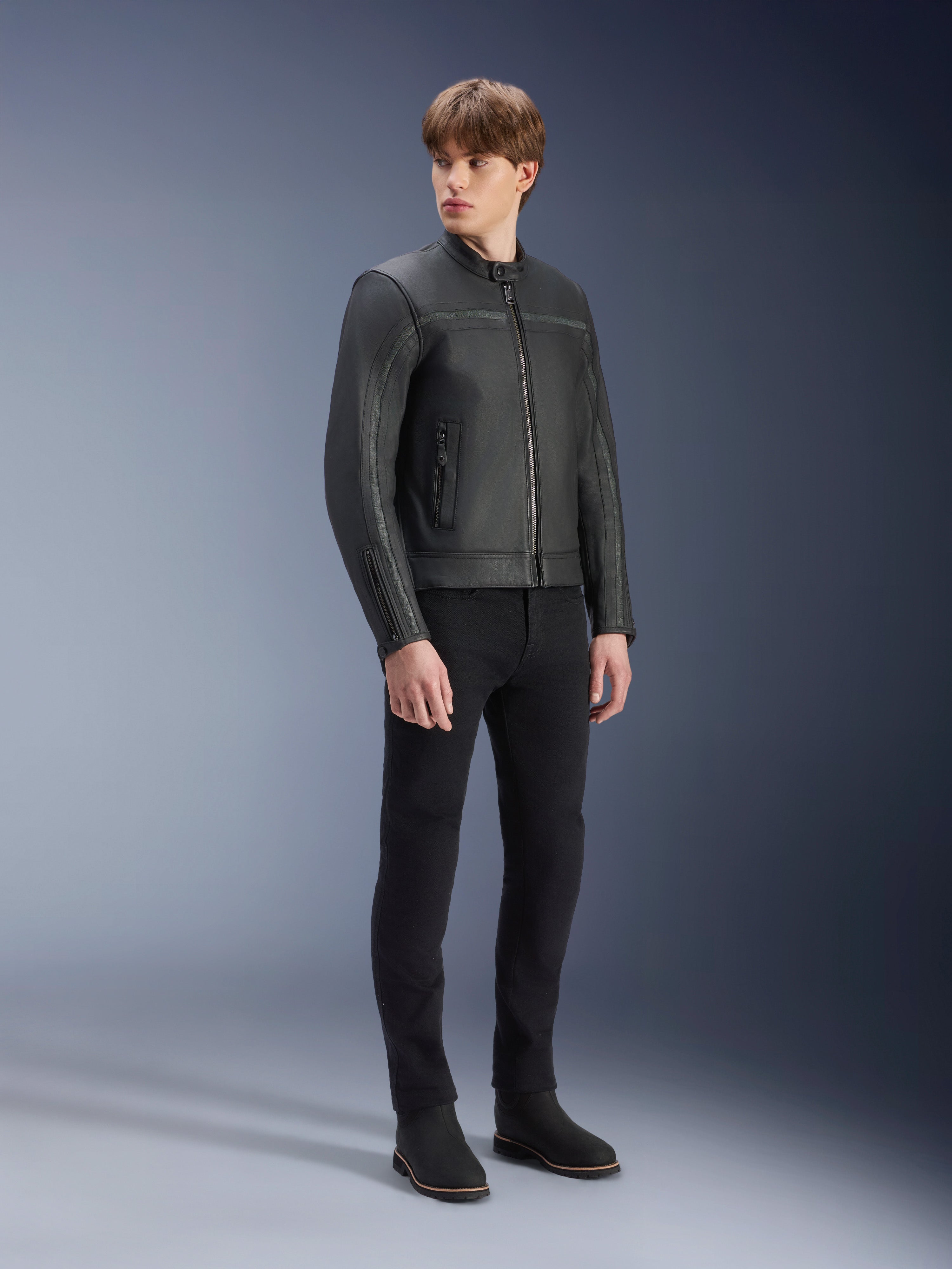 Giacca in pelle Alpinestars Dyno nero, giacca da moto in pregiata pelle bovina, indossata da un modello con pantaloni neri slim-fit e stivali neri, design minimalista d'ispirazione heritage per uno stile urban contemporaneo, ambientazione in studio.