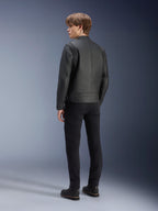 Giacca in pelle Alpinestars Dyno, nero, indossata da un modello uomo, vista posteriore, con pannelli a coste sulle spalle, abbinata a pantaloni e stivali neri, stile motociclistico urbano d'ispirazione heritage