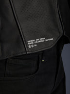Primo piano della giacca in pelle Alpinestars Atem V5 in nero, con pannello posteriore inferiore, marchio 'ONE GOAL. ONE VISION. VENICE / LOS ANGELES CALIFORNIA' e trama in pelle traforata.