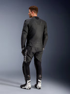 Giacca in pelle Alpinestars Caliber, giacca da moto stradale nera, vista posteriore, con pelle traforata e inserti a soffietto elasticizzati su vita e spalle, logo a rilievo, indossata con pantaloni in pelle neri e stivali da corsa bianchi
