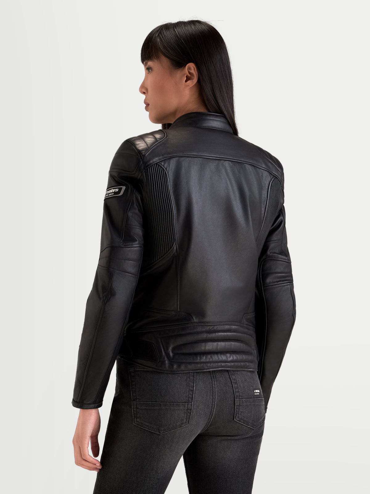 Alpinestars Revea Donna Giacca di pelle, giacca da moto urbana in pelle da donna, colore nero, vista posteriore con struttura in pelle bovina pieno fiore e imbottitura sulle spalle indossata da una modella