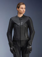 Giacca in pelle Alpinestars Stella GP Plus V4, nera, giacca da moto racing da donna, struttura in pelle premium con imbottitura protettiva, design elegante con logo discreto, indossata da una modella con equipaggiamento nero coordinato