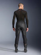 Pantaloni in pelle Alpinestars Missile V3, nero, vista posteriore su modello che indossa una maglia a compressione nera a maniche lunghe e stivali racing, costruzione in pelle premium con sovrapposizione a vita alta e zone elasticizzate, abbigliamento professionale da motociclismo