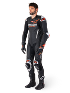 Alpinestars tuta in pelle GP-R7 1 Pezzo, tuta da moto racing da uomo nera, bianca e rossa fluo, pelle traforata, indossata con guanti e stivali neri.