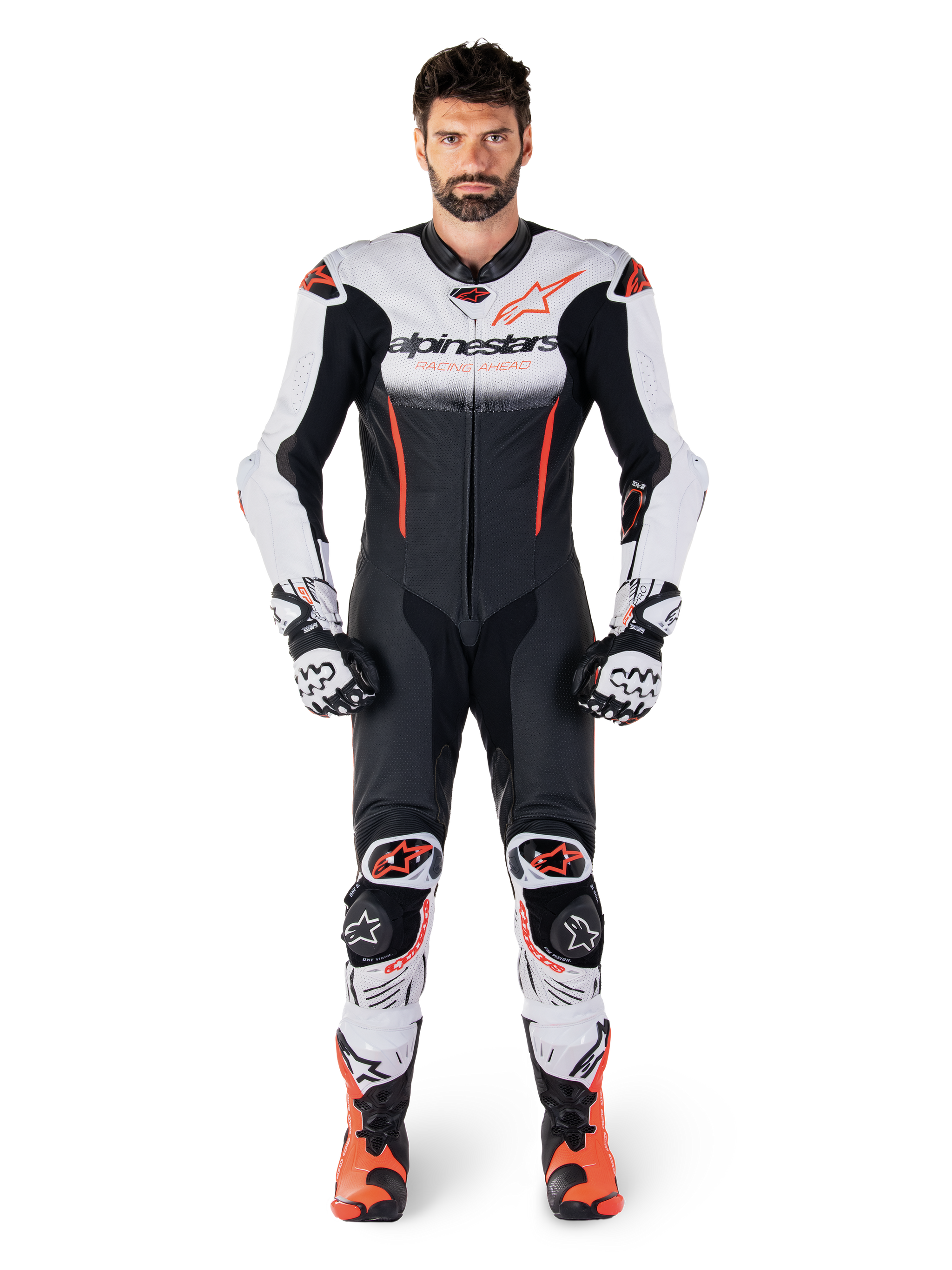 Pilota uomo che indossa la tuta in pelle intera Alpinestars GP-R7 in bianco, nero e rosso fluo, coordinata con guanti e stivali racing abbinati, equipaggiamento professionale da pista con vestibilità da gara aerodinamica e loghi evidenti