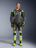 Alpinestars GP Tech V5 One Piece Leather Suit, tuta professionale da moto in pelle monopezzo, nero e giallo neon fluo con dettagli bianchi, indossata da un modello con guanti e stivali da corsa coordinati, design aerodinamico e slider protettivi