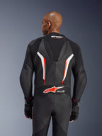Tuta in pelle Alpinestars GP Force V2, tuta da moto intera, nero, bianco e rosso fluo, vista posteriore della parte superiore del corpo che mostra la pelle traforata e il logo Tech-Air Ready, indossata con guanti coordinati neri e rossi