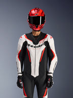 Alpinestars GP Force V2 Leather Suit - Monopezzo, Bianco Nero Rosso Fluo, indossata con casco integrale rosso e guanti da corsa neri, con pannelli in pelle traforata e logo Alpinestars sul petto, abbigliamento professionale per competizioni motociclistiche