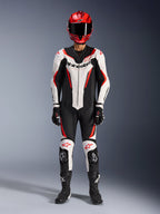 Tuta in pelle Alpinestars GP Force V2 monopezzo, bianco, nero e rosso fluo, equipaggiamento racing completo con casco rosso, guanti e stivali neri, caratterizzata da design aerodinamico e loghi Alpinestars su petto e ginocchia