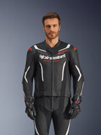 Tuta in pelle Alpinestars GP Force V2 2 pezzi, nero, bianco e rosso fluo, vista frontale di un modello che indossa la tuta in pelle traforata con guanti neri coordinati, con accenti bianchi angolari e logo Alpinestars sul petto
