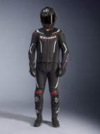Alpinestars GP Force V2 Leather Suit 2 pezzi, tuta racing da moto, nero, bianco e rosso fluo, con logo Alpinestars bianco sul petto e accenti rossi su spalle e ginocchia, indossata con casco integrale nero, guanti neri e stivali neri per un set completo di equipaggiamento ad alte prestazioni