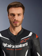 Alpinestars GP Force V2 2-Piece, giacca della tuta in pelle, nero bianco rosso fluo, primo piano con pelle traforata, logo Alpinestars bianco e scritta rossa 'RACING AHEAD', abbigliamento tecnico da moto