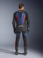 Tuta in pelle Alpinestars GP Force V2 2 pezzi, vista posteriore, nero blu e rosso fluo, con pannelli in pelle blu sulla schiena e sulle gambe con accenti rosso fluorescente, logo Tech-Air Ready sulla parte bassa della schiena, indossata con guanti e stivali da corsa neri.