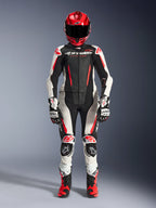 Tuta in pelle Alpinestars Stella GP-R7 Donna 2 Pezzi, nero, bianco e rosso fluo, vista a corpo intero di una pilota con casco, guanti e stivali da corsa coordinati, con pannelli traforati e design aerodinamico per pista e strada.