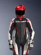 Motociclista donna con tuta in pelle Alpinestars Stella GP-R7 2 Pezzi, colori Nero Bianco e Rosso Fluo, con pannelli traforati e branding 'Racing Ahead', indossata con casco rosso e guanti GP Pro bianchi e neri, equipaggiamento da corsa professionale