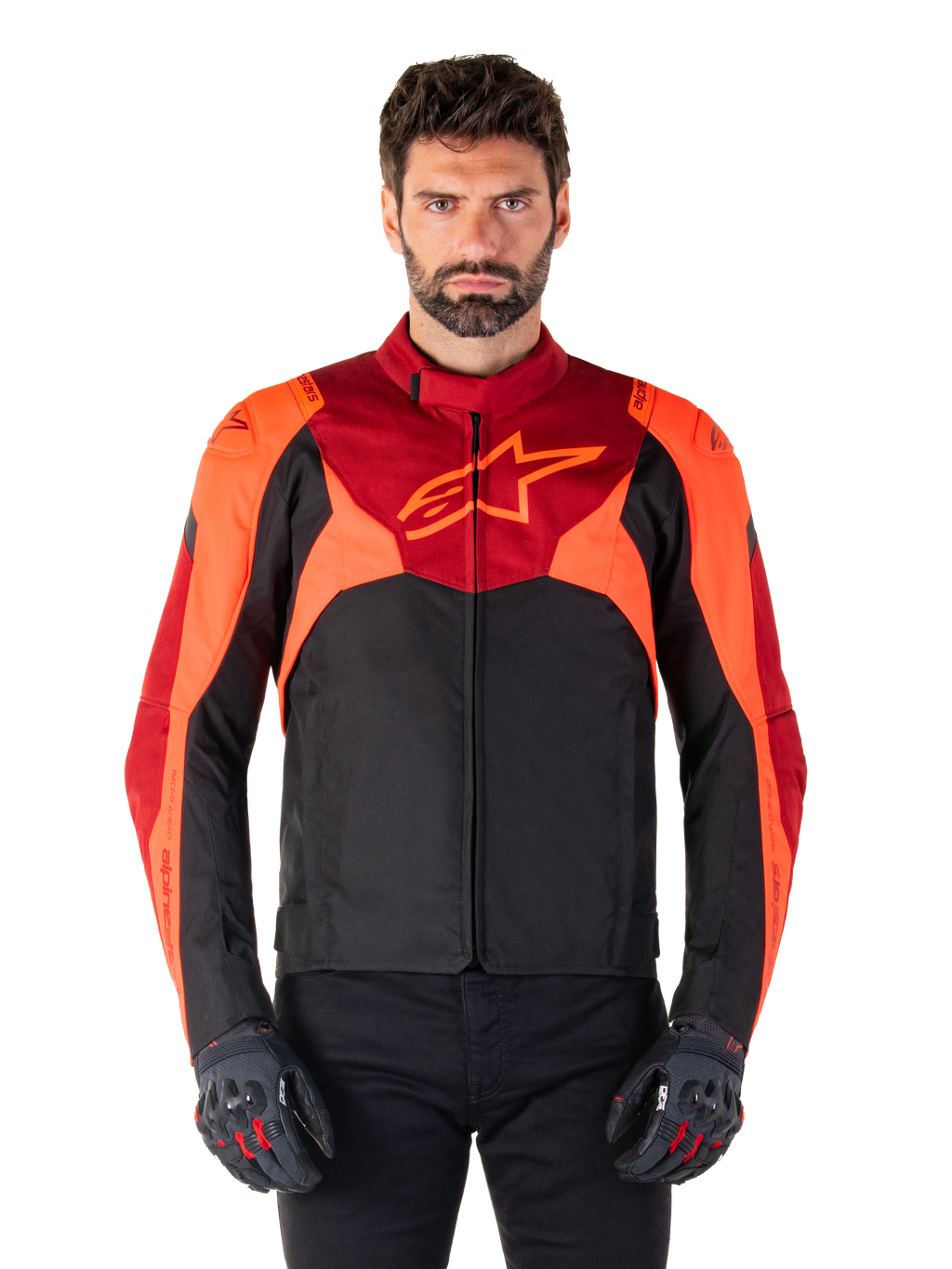 Giacca Alpinestars T-Jaws V4 Waterproof, giacca da moto sportiva in tessuto, nero con accenti rosso fluo e rosso scuro, indossata da un modello con guanti coordinati, abbigliamento tecnico con logo a stella sul petto