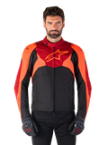 Giacca Alpinestars T-Jaws V4 Waterproof, giacca da moto sportiva in tessuto, nero con accenti rosso fluo e rosso scuro, indossata da un modello con guanti coordinati, abbigliamento tecnico con logo a stella sul petto