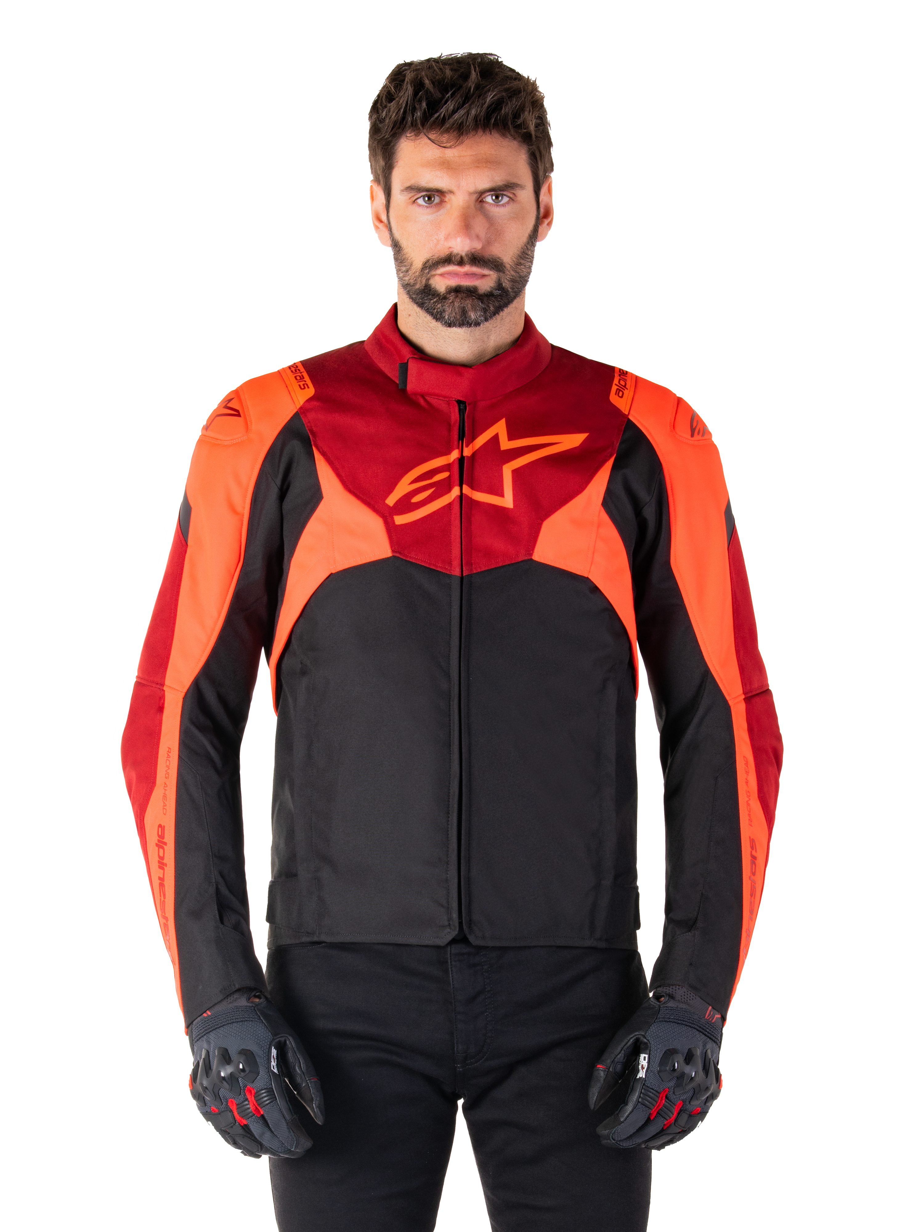 Giacca Alpinestars T-Jaws V4 Waterproof, giacca da moto sportiva in tessuto, nero con accenti rosso fluo e rosso scuro, indossata da un modello con guanti coordinati, abbigliamento tecnico con logo a stella sul petto