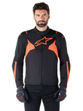 Giacca impermeabile Alpinestars T-Jaws V4, giacca sportiva da moto, nero e rosso fluo, con accenti neon e un prominente logo a stella sul petto, indossata da un modello uomo con guanti da moto neri, design in tessuto elegante d'ispirazione racing
