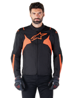 Giacca impermeabile Alpinestars T-Jaws V4, giacca sportiva da moto, nero e rosso fluo, con accenti neon e un prominente logo a stella sul petto, indossata da un modello uomo con guanti da moto neri, design in tessuto elegante d'ispirazione racing