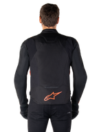 Giacca impermeabile Alpinestars T-Jaws V4, vista posteriore, nero con rosso fluo, con logo Alpinestars rosso sulla parte bassa della schiena, struttura in tessuto tecnico, indossata con pantaloni e guanti neri per un look da guida sportiva completo