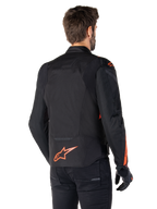 Modello che indossa la giacca Alpinestars T-Jaws V4 Waterproof vista da dietro, nera con accenti rosso fluo, con un logo rosso fluo sulla parte bassa della schiena e accenti su spalle e maniche, abbigliamento sportivo da moto.