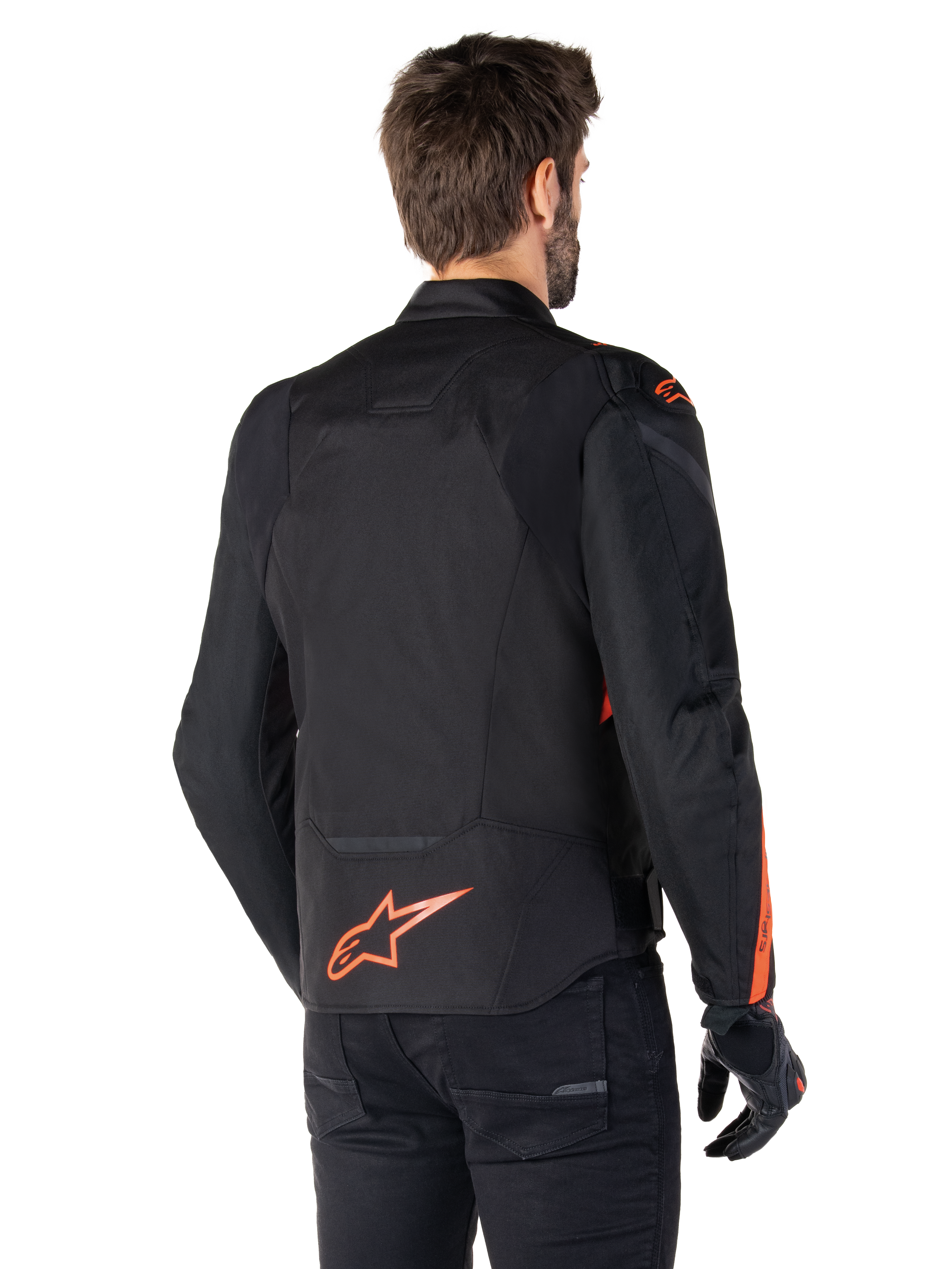Modello che indossa la giacca Alpinestars T-Jaws V4 Waterproof vista da dietro, nera con accenti rosso fluo, con un logo rosso fluo sulla parte bassa della schiena e accenti su spalle e maniche, abbigliamento sportivo da moto.