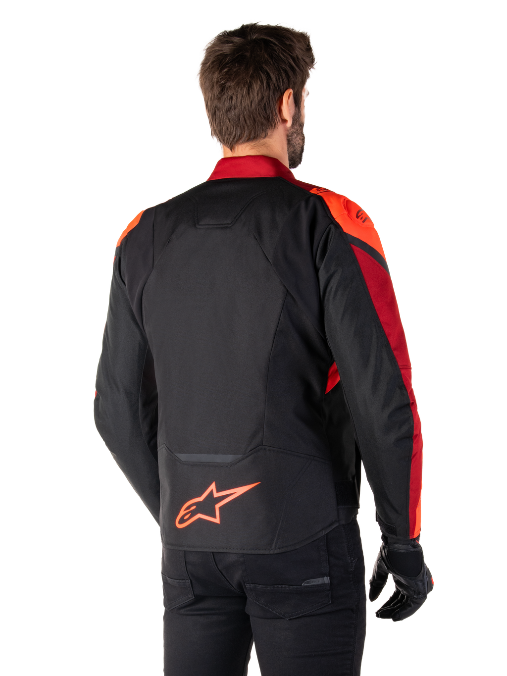 Vista posteriore di un uomo che indossa la giacca Alpinestars T-Jaws V4 Waterproof in Black Red Fluo Dark Red, con vivaci accenti rossi su spalle e maniche, logo Alpinestars rosso fluo sulla parte bassa della schiena, abbinata a pantaloni e guanti neri