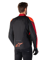 Vista posteriore di un uomo che indossa la giacca Alpinestars T-Jaws V4 Waterproof in Black Red Fluo Dark Red, con vivaci accenti rossi su spalle e maniche, logo Alpinestars rosso fluo sulla parte bassa della schiena, abbinata a pantaloni e guanti neri
