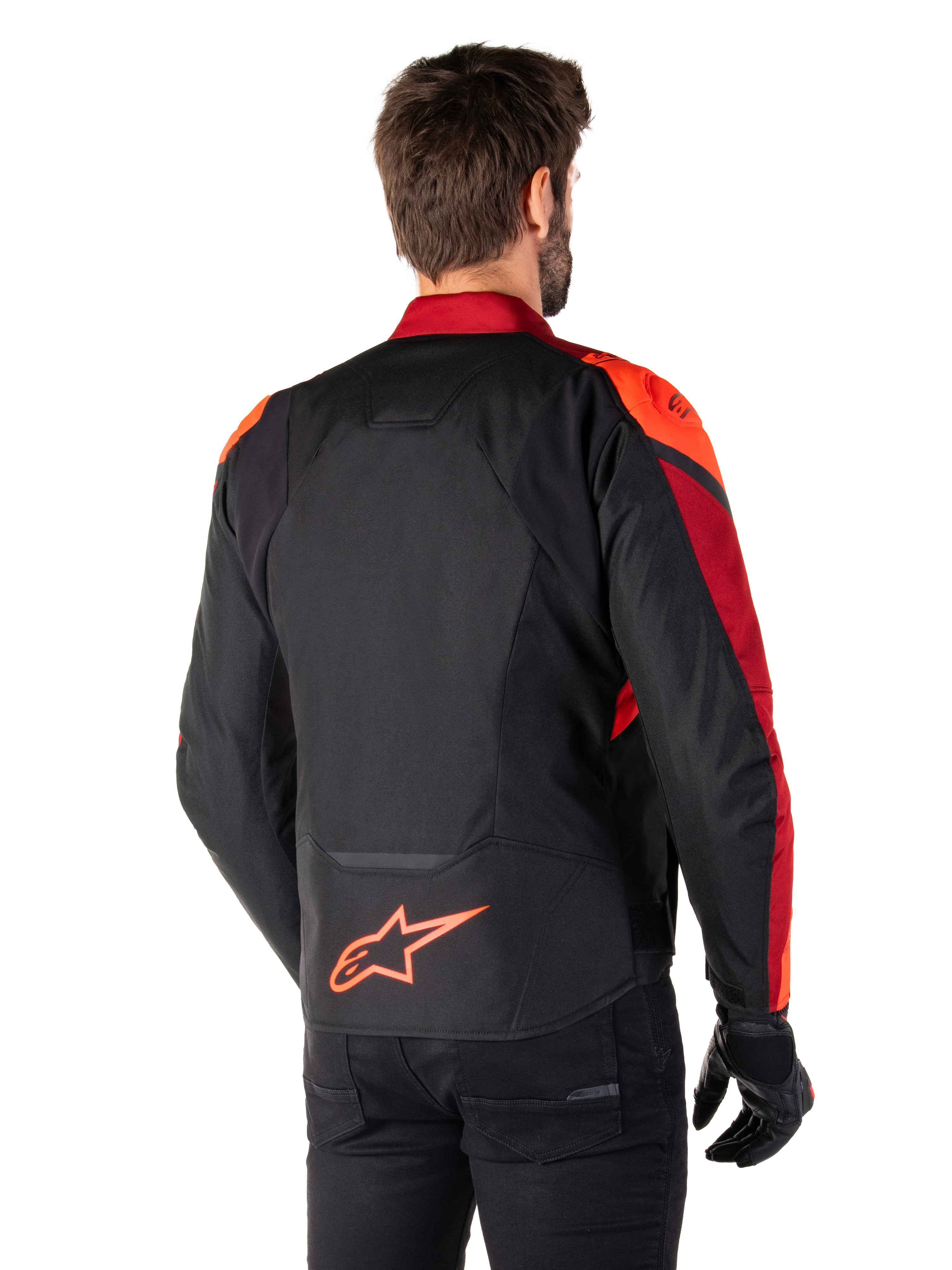 Vista posteriore di un uomo che indossa la giacca Alpinestars T-Jaws V4 Waterproof in Black Red Fluo Dark Red, con vivaci accenti rossi su spalle e maniche, logo Alpinestars rosso fluo sulla parte bassa della schiena, abbinata a pantaloni e guanti neri
