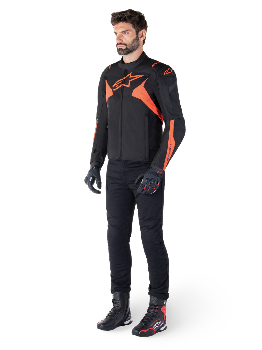 Giacca Alpinestars T-Jaws V4 Waterproof, nero e rosso fluo, indossata da un modello con pantaloni, guanti e stivali neri, con vivaci dettagli arancioni e il logo Alpinestars, design sportivo per la guida in moto