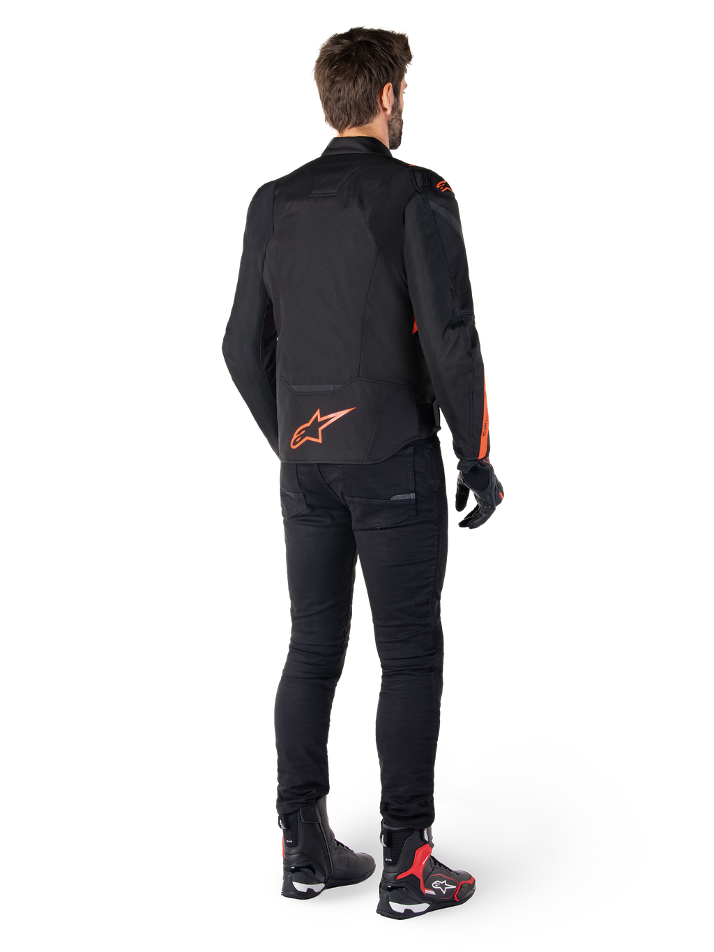 Giacca Alpinestars T-Jaws V4 Waterproof, nero e rosso fluo, vista posteriore indossata da un motociclista, con un vivace logo rosso fluo sulla schiena, abbinata a pantaloni da moto neri e stivali tecnici, abbigliamento sportivo da moto