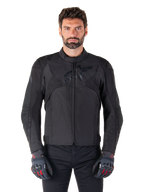 Giacca impermeabile Alpinestars T-Jaws V4, giacca da moto sportiva nera, indossata da un uomo con guanti neri e dettagli rossi, spalle e braccia rinforzate, design elegante con logo discreto sul petto, abbigliamento da moto in tessuto per tutte le stagioni