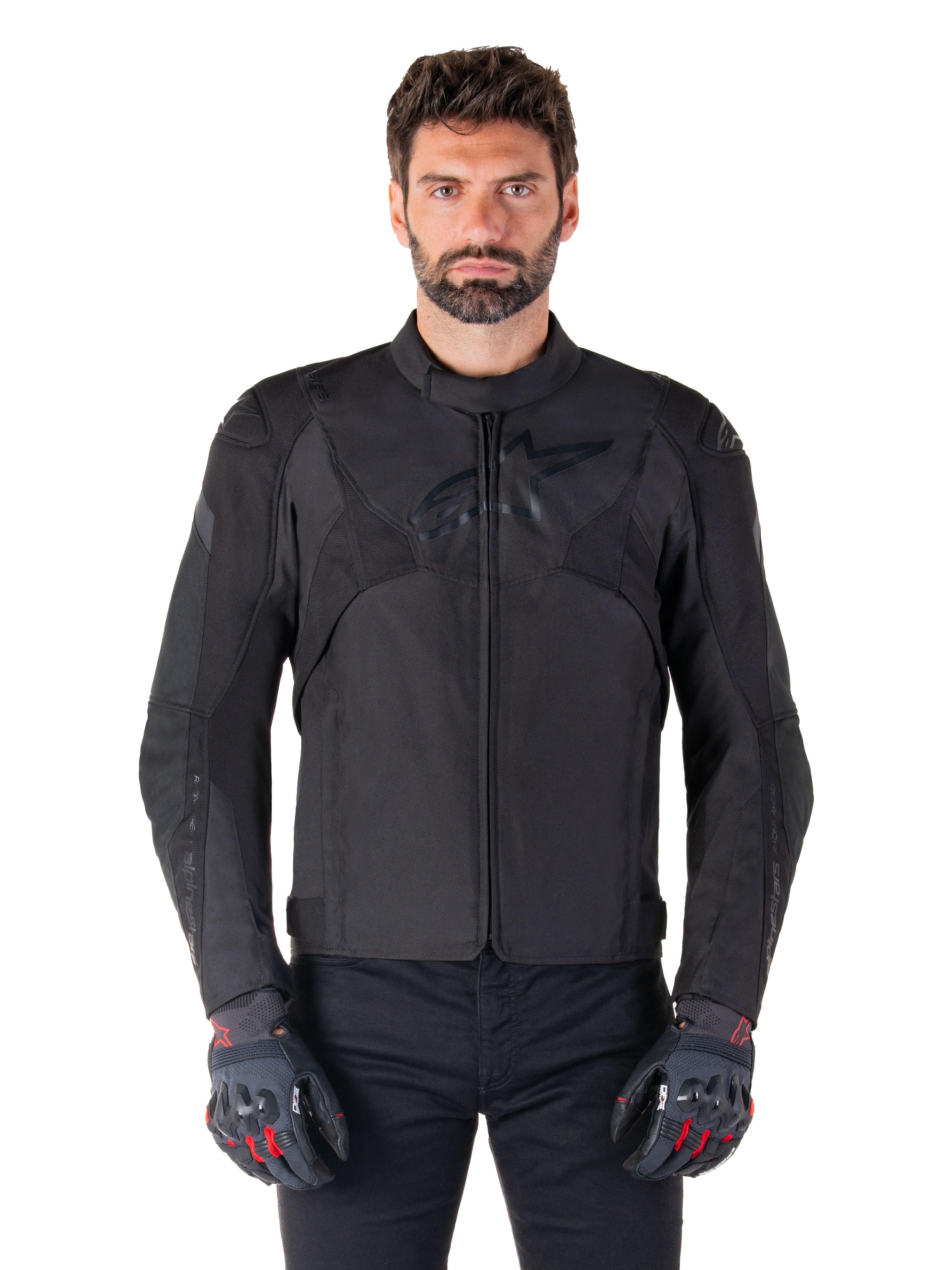 Giacca impermeabile Alpinestars T-Jaws V4, giacca da moto sportiva nera, indossata da un uomo con guanti neri e dettagli rossi, spalle e braccia rinforzate, design elegante con logo discreto sul petto, abbigliamento da moto in tessuto per tutte le stagioni