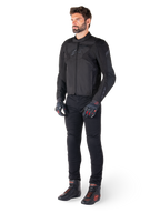Modello maschile che indossa la giacca Alpinestars T-Jaws V4 Waterproof in nero, abbinata a pantaloni da guida neri, guanti neri con accenti rossi e scarpe da moto nere, con una vestibilità sportiva e loghi discreti, isolato su sfondo bianco.