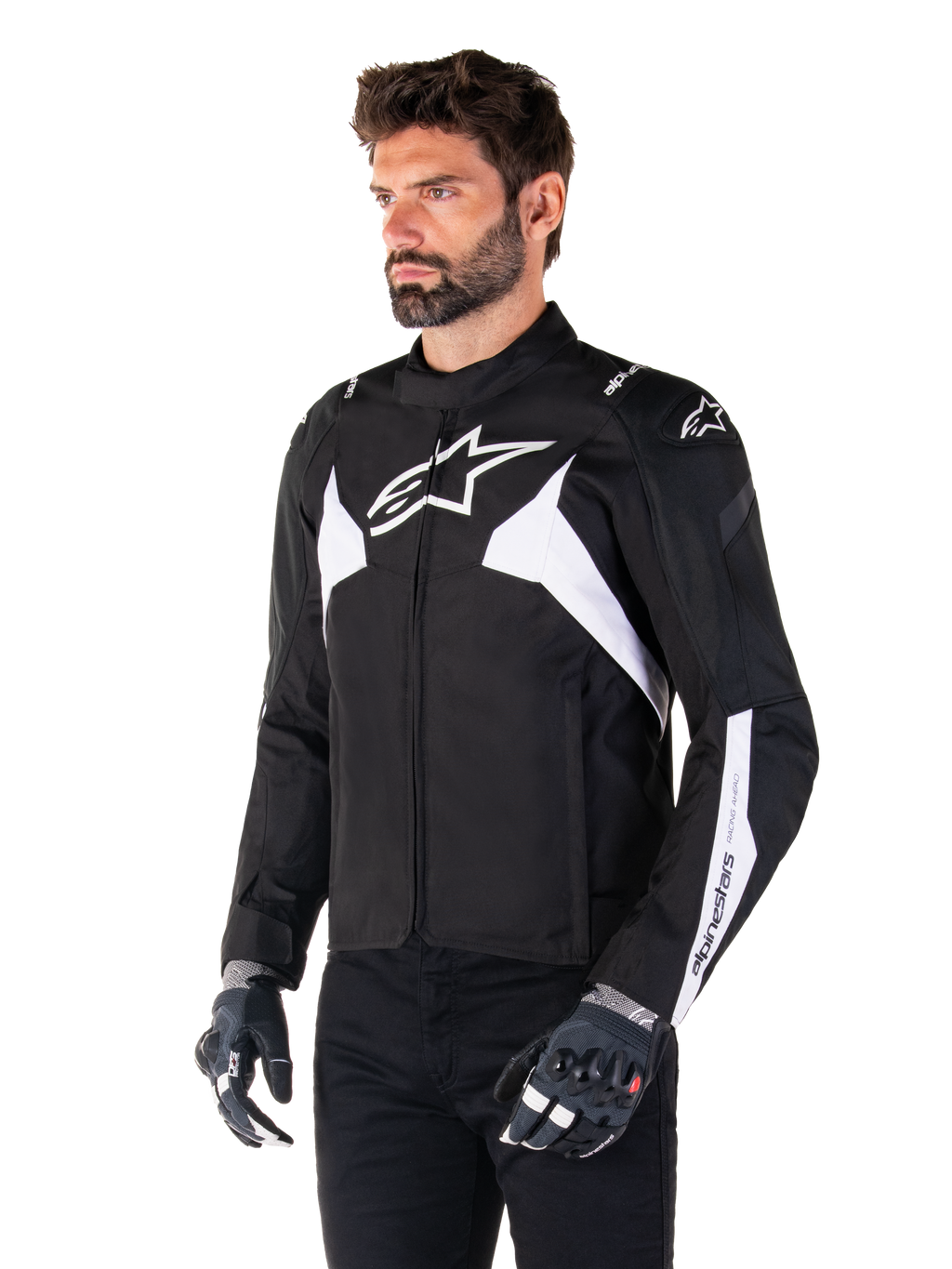 Giacca Alpinestars T-Jaws V4 Waterproof, nero e bianco, indossata da un modello con guanti da moto, con loghi Alpinestars e dettagli bianchi in evidenza, giacca da moto in tessuto con vestibilità sportiva per la guida su strada