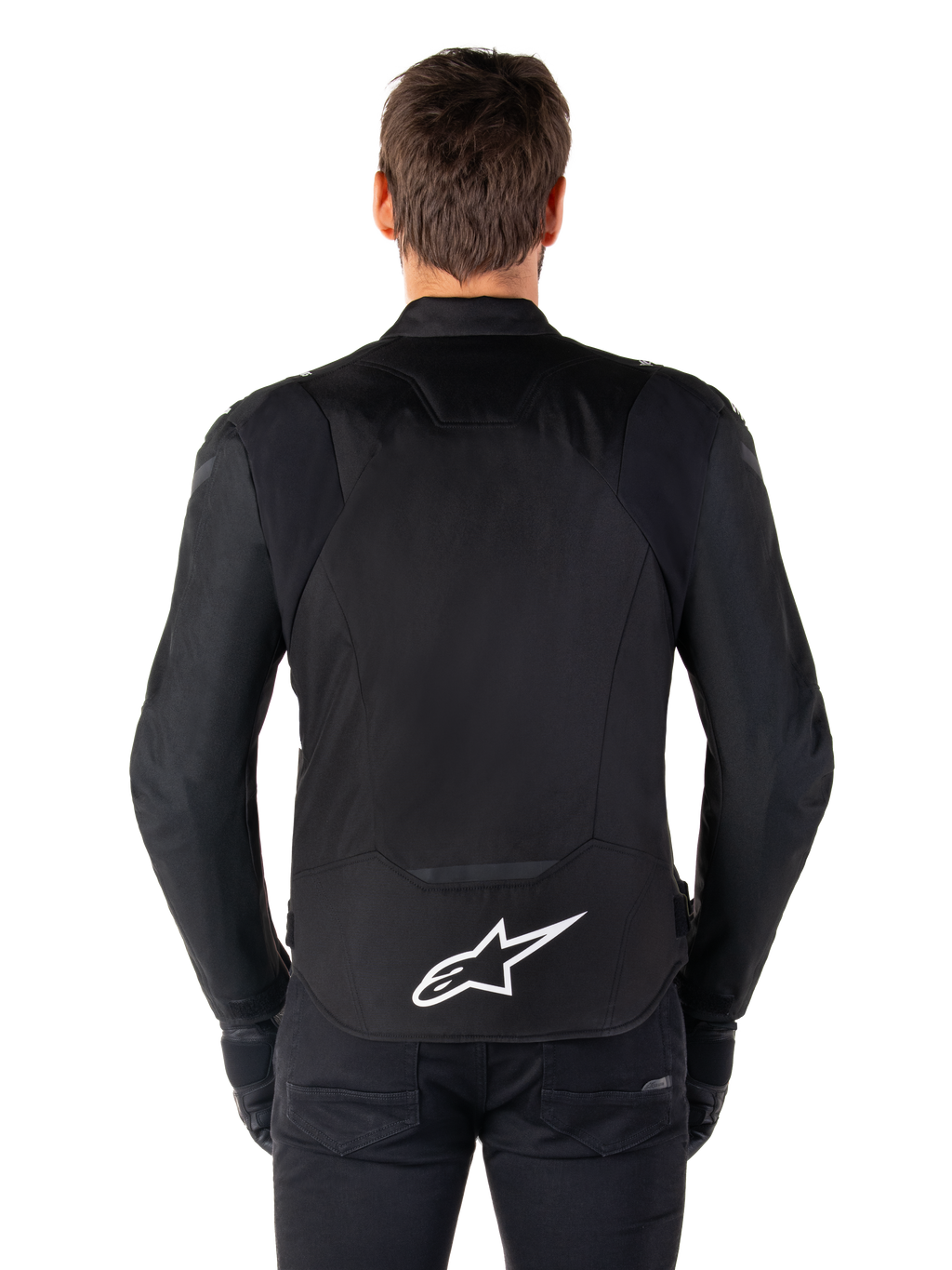 Giacca Alpinestars T-Jaws V4 Waterproof, giacca da moto nera vista dal retro, logo Alpinestars bianco sulla parte bassa della schiena, schiena allungata per maggiore copertura, indossata con pantaloni e guanti neri, design sportivo in tessuto