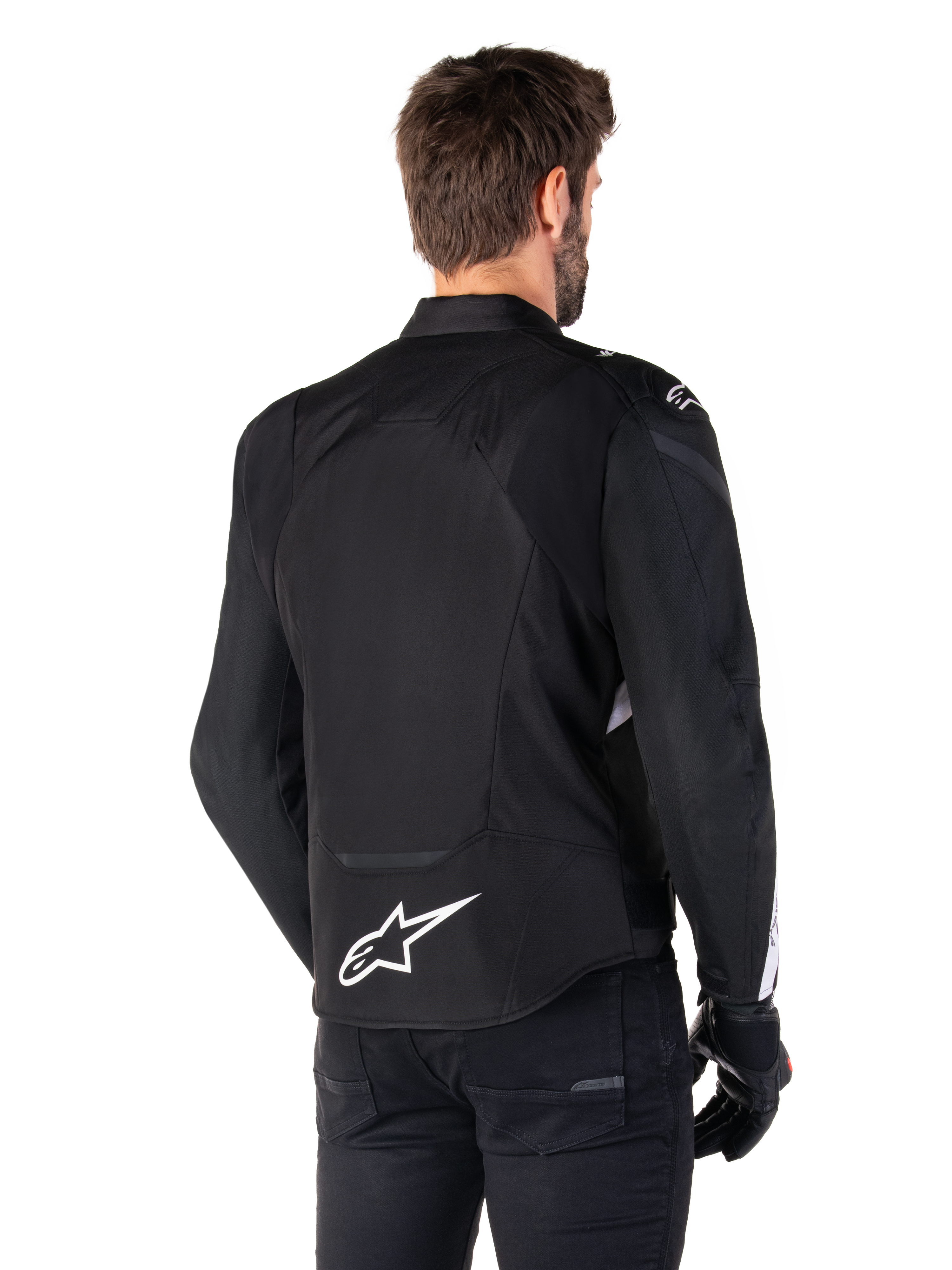 Alpinestars Giacca Impermeabile T-Jaws V4, nero e bianco, vista posteriore, giacca da moto sportiva in tessuto con logo bianco sulla parte bassa della schiena, indossata con guanti e pantaloni neri, con silhouette dalla vestibilità sportiva rivista