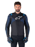 Giacca Alpinestars T-Jaws V4 Waterproof, giacca da moto, nero e blu scuro con accenti blu Blithe, logo bianco sul petto, scritte blu sulle spalle, indossata con guanti abbinati, abbigliamento tecnico da moto in tessuto impermeabile