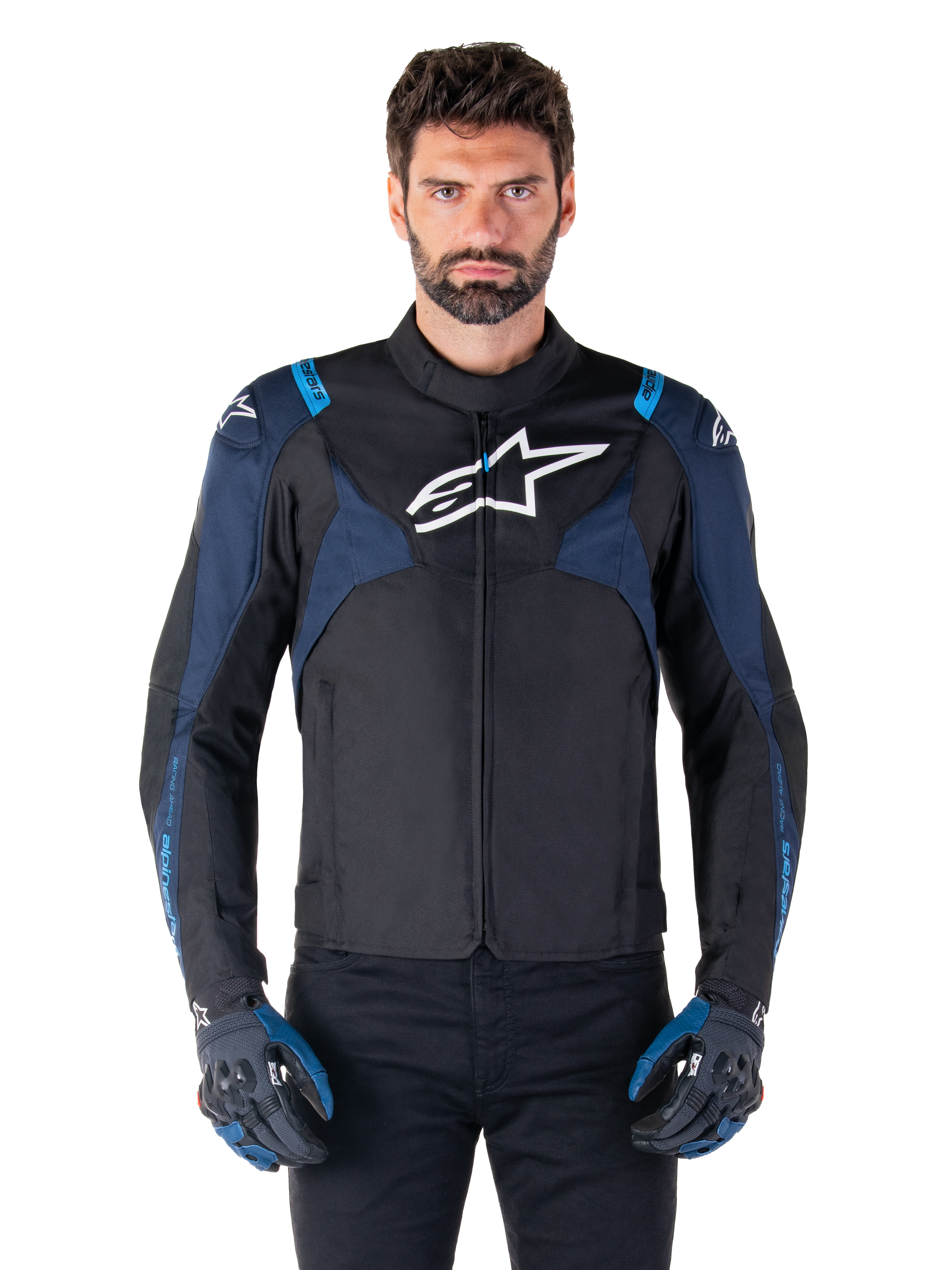 Giacca Alpinestars T-Jaws V4 Waterproof, giacca da moto, nero e blu scuro con accenti blu Blithe, logo bianco sul petto, scritte blu sulle spalle, indossata con guanti abbinati, abbigliamento tecnico da moto in tessuto impermeabile